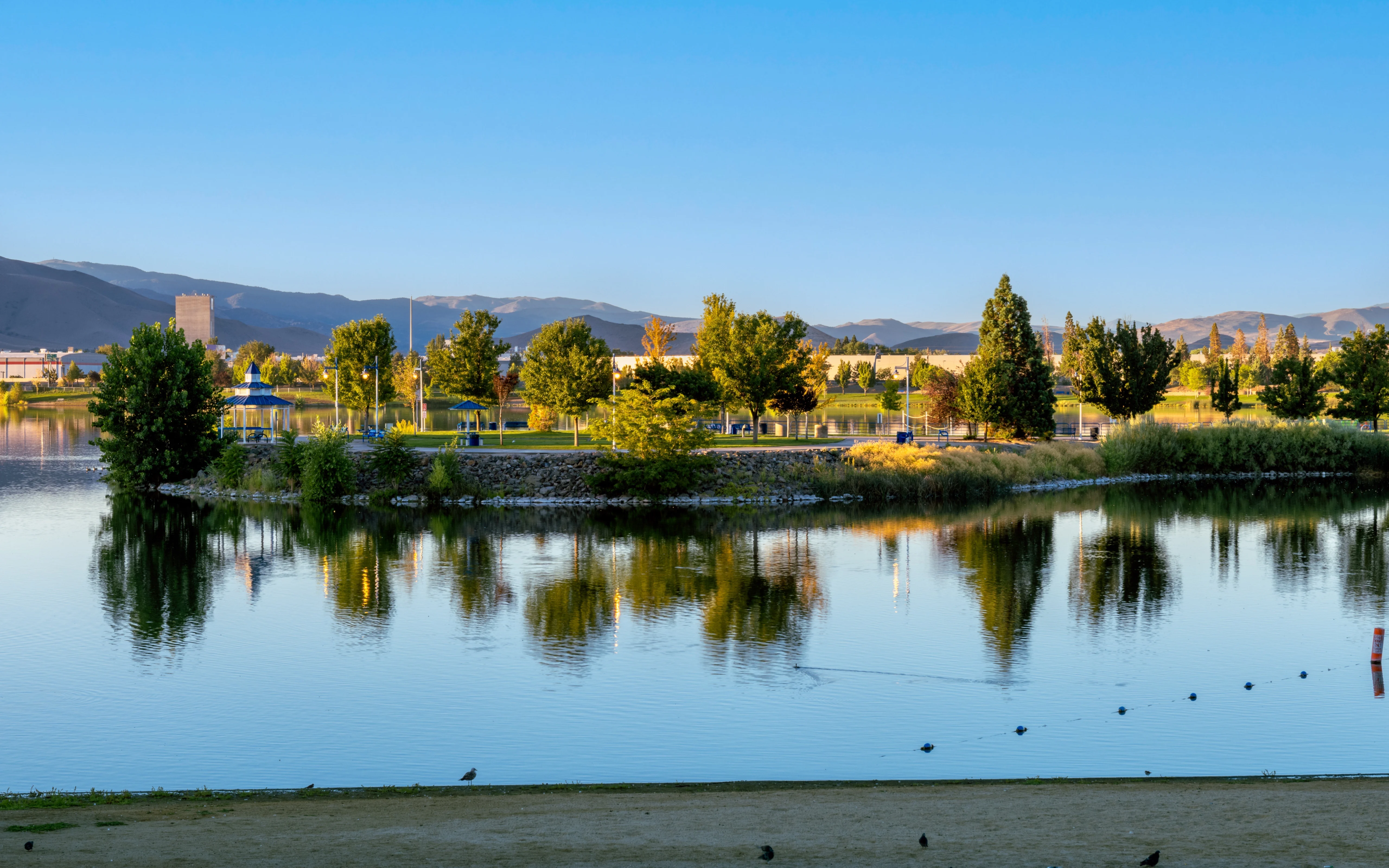 Sparks Marina Park During Golden Hour in Late Summer with Birds in the Water, a Clear Blue Sky and Mountains in the Background.